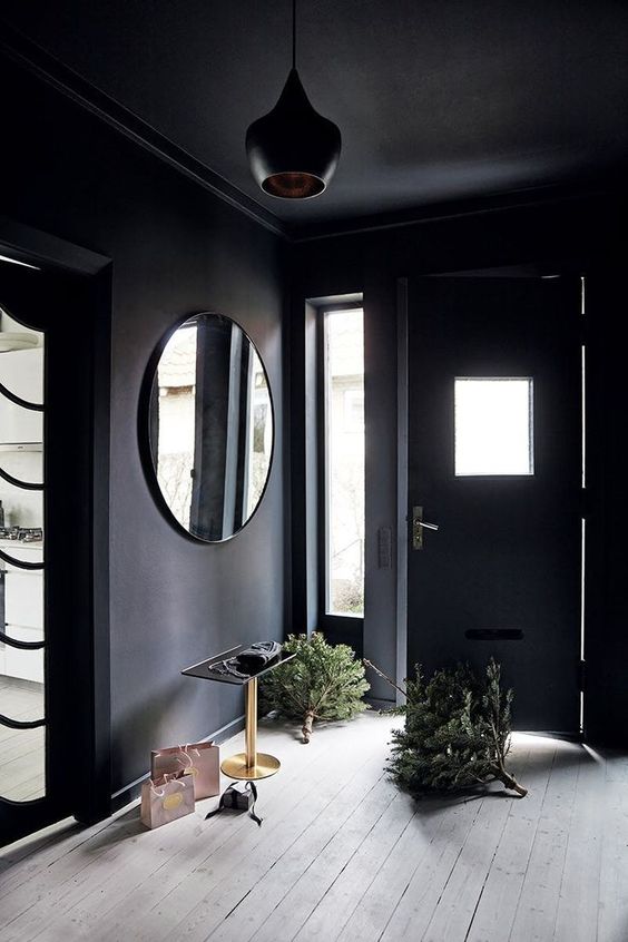 a soot entryway with a round mirror, a table and a beautiful black pendant lamp is amazing and super chic