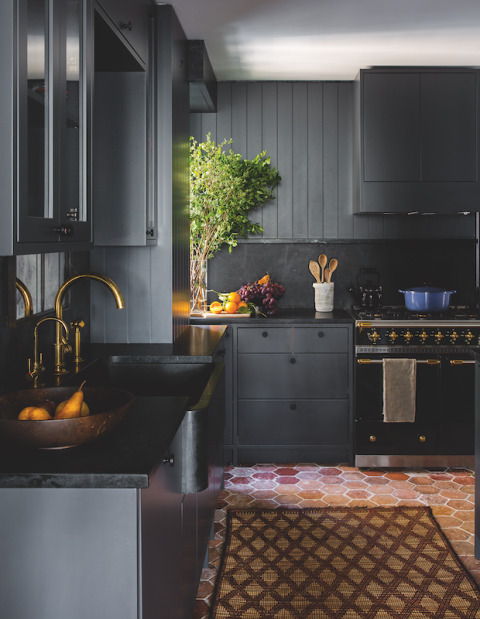 a soot farmhouse kitchen with smooth cabinets, ribbed shiplap walls and black stone countertops plus a backsplash
