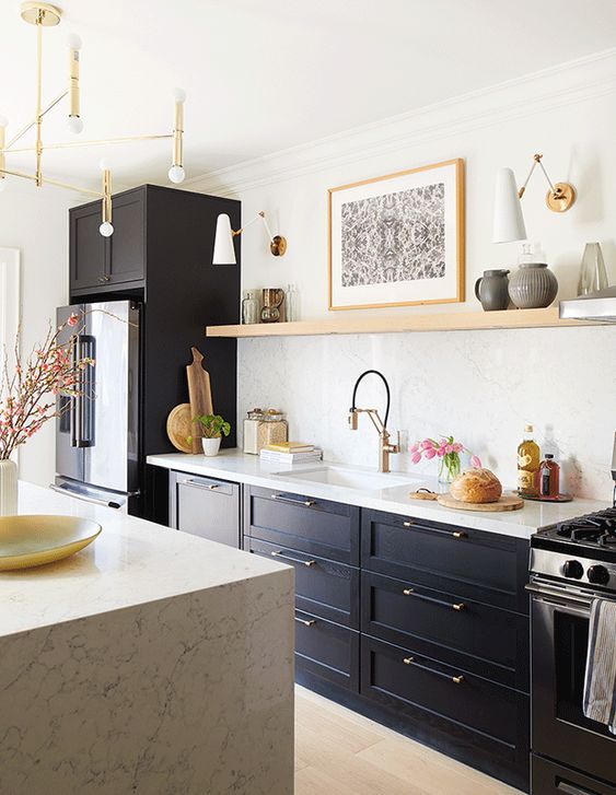 a soot kitchen with an open shelf instead of upper cabinets, a kitchen island with a white stone counter and some gold touches