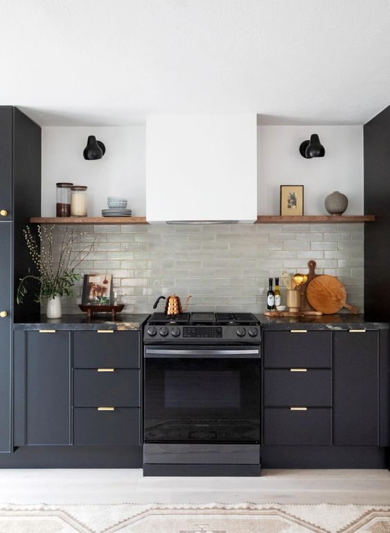 a soot kitchen with gold handles, a white hood, open shelves, black sconces and decor, artwork is a stylish idea