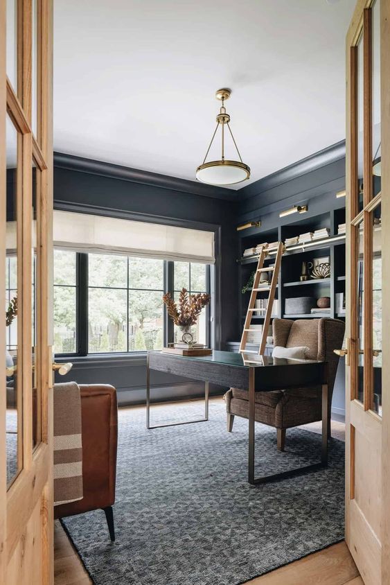 a soot modern farmhouse home office with soot walls and matching cabinets, a dark-stained desk, a beige chair and brown leather ones