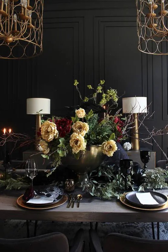 a sophisticated Halloween tablescape with yellow and burgundy blooms, eucalyptus, gold chargers and cutlery, candles
