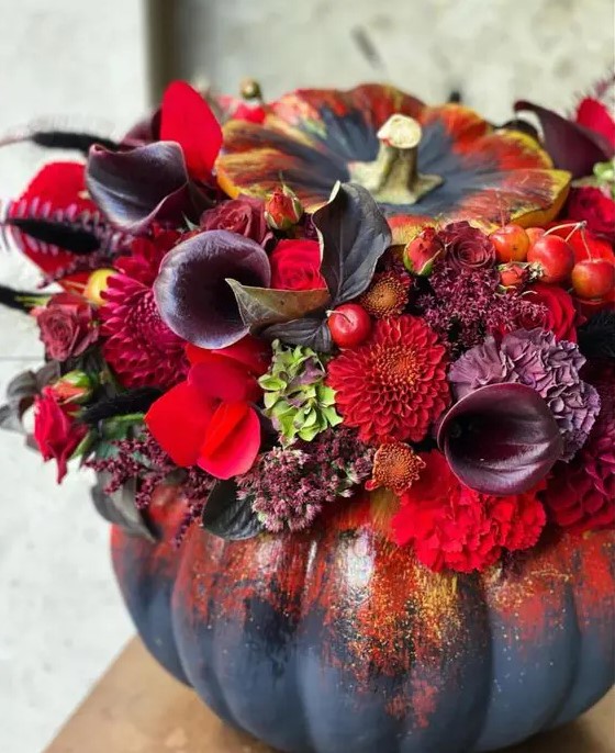a sophisticated black Halloween pumpkin done with red, burgundy, deep purple blooms, foliage and berries