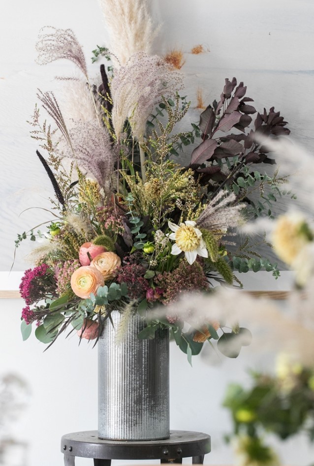 a stunning dark Halloween floral arrangement with eucalyptus, yellow and peachy blooms, dark leaves and purple grasses
