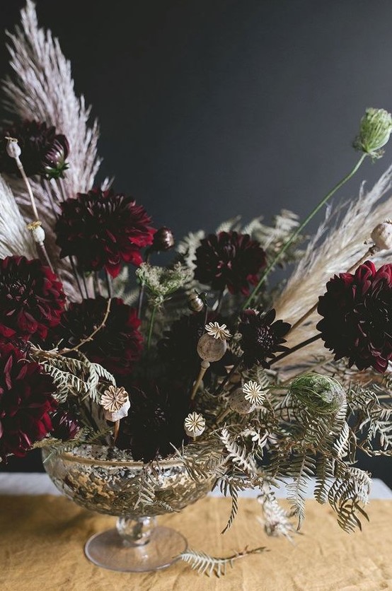 a super elegant Halloween centerpiece of a silver bowl and moody florals plus white dried herbs and greenery