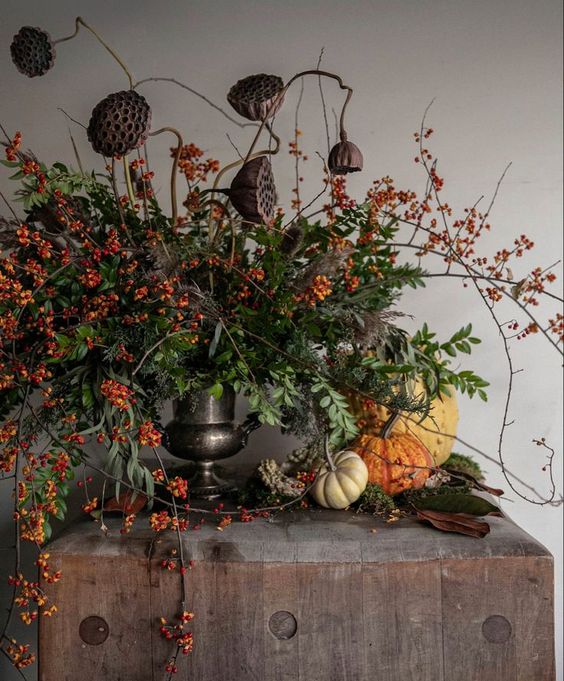 a unique Halloween flower arrangement of berries, greenery, twigs and lotus slices is amazing for the fall, too