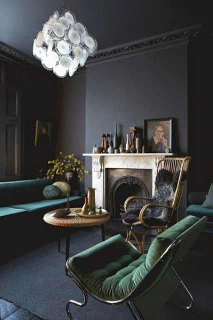 a vintage soot living room with a fireplace, a green sofa and green chairs, a rattan chair, a coffee table and somevases