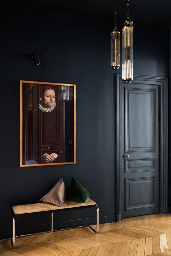 an elegant and chic soot entryway with a cane bench and pillows, a vintage artwork and pendant lamps