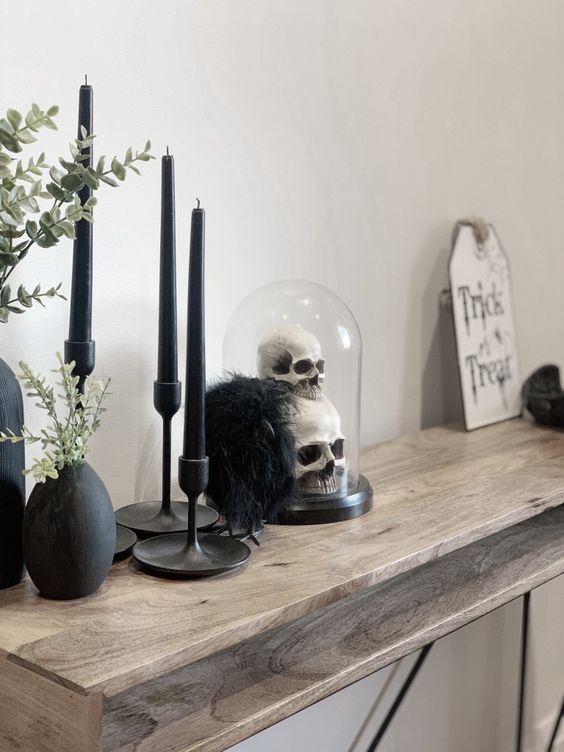 modern Halloween decorating with black candles, a cloche with skulls, greenery and some decor is a fast to realize idea
