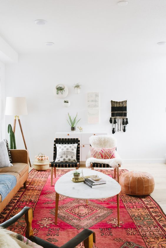 a bright boho living room with an amber leather sofa, bright pillows, a coffee table, a leather pouf and macrame on the wall