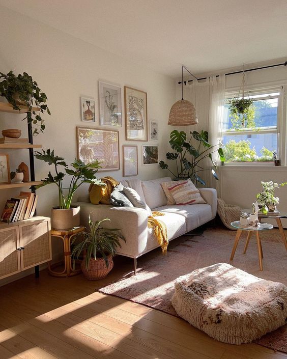 a modern boho living room with a white sofa, a gallery wall, a woven pendant lamp, a duo of coffee tables, a cushion and a shelving unit