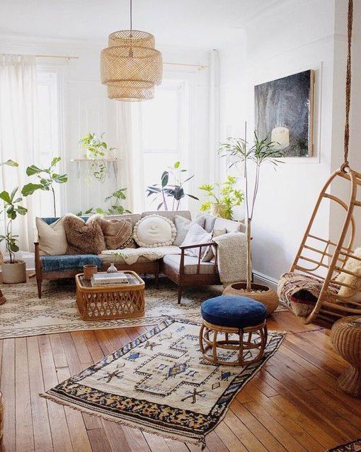 a relaxed boho living room with a sectional, pillows, printed rugs, a coffee table, potted plants and a pendant chair