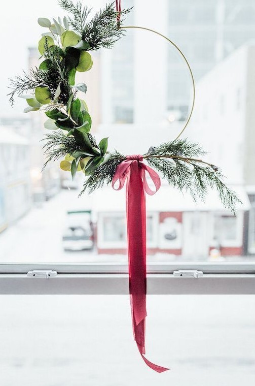 a Christmas wreath with evergreens, leaves and a red ribbon bow is a laconic holiday decoration to rock