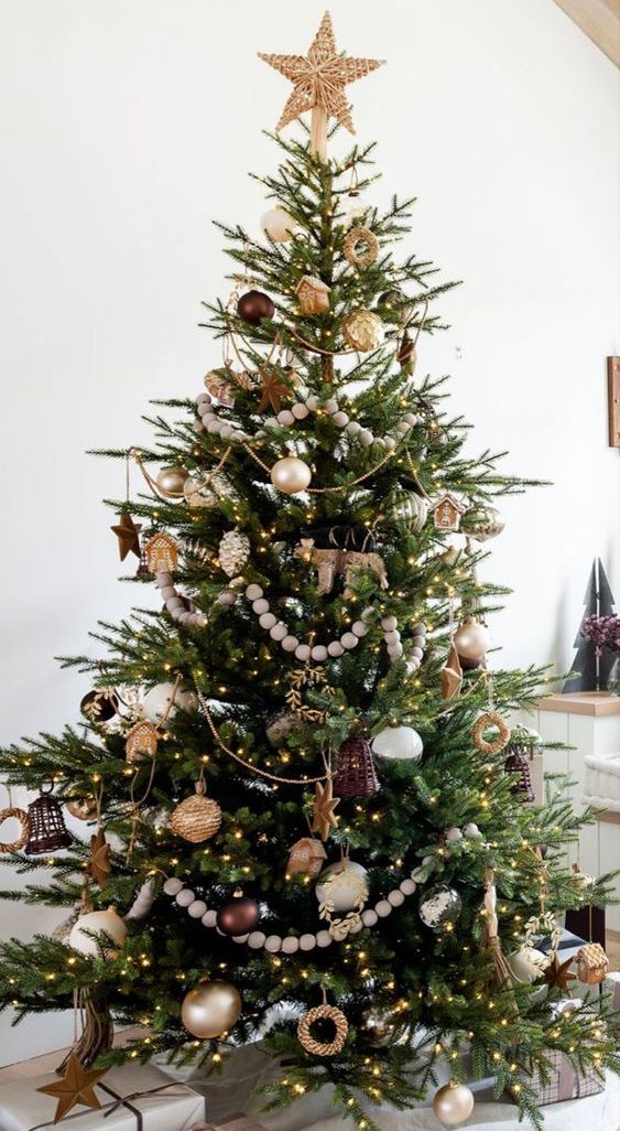 a beautiful boho Christmas tree with wooden beads, hoses, stars, Christmas ornaments and lights is a cool idea