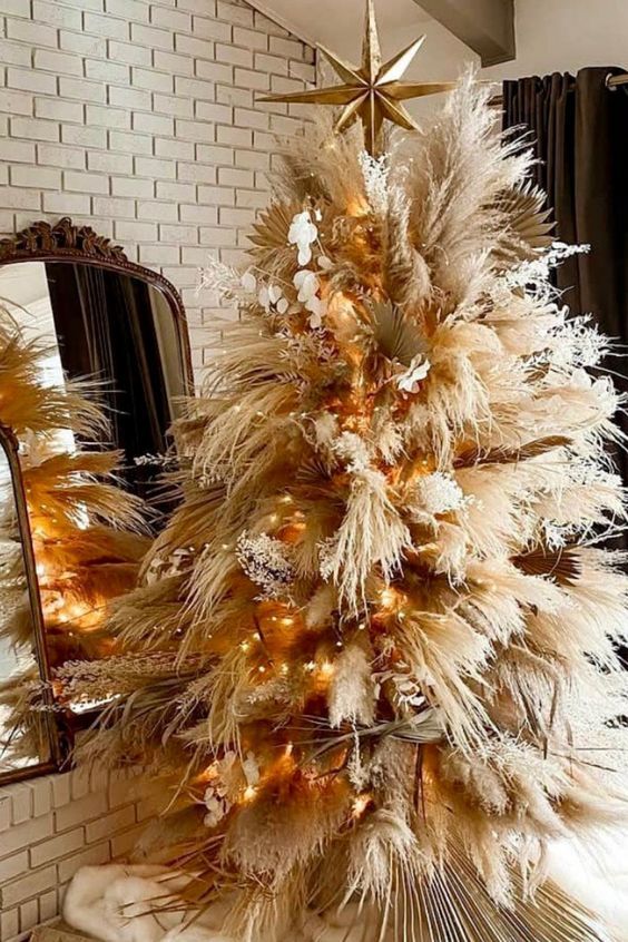 a boho Christmas tree with pampas grass and fronds, lunaria, lights and a large gold star on top