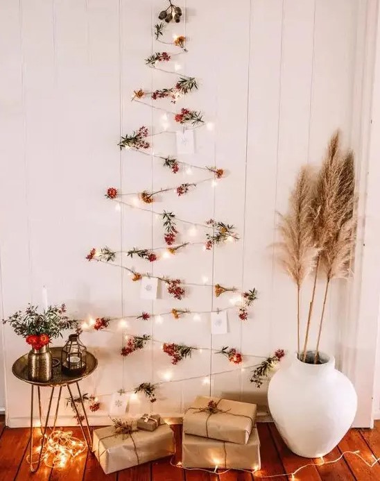 a boho wall-mounted Christmas tree of lights, berries and Christmas cards plus pampas grass and blooms around