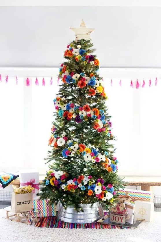 a bright Christmas tree with orange, pink, blue, white and yellow faux blooms and a wooden star topper is gorgeous