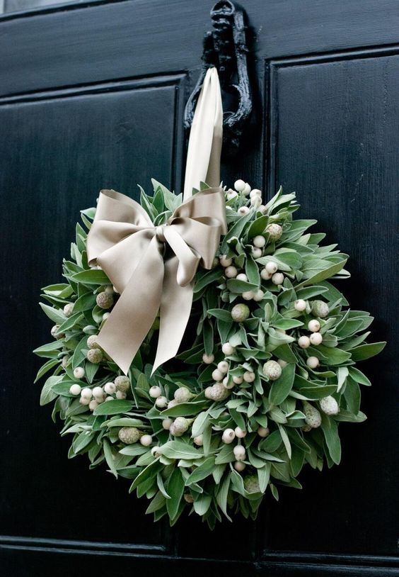 a catchy modern Christmas wreath with lots of greenery, white berries and a neutral silk ribbon bow is amazing