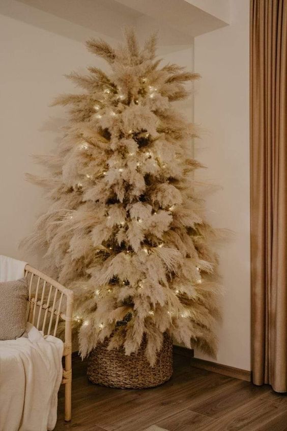 a classy boho Christmas tree with pampas grass and lights put in a basket is a cool idea for a boho space