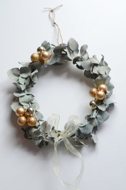 a cool Christmas wreath of dried eucalytus, gold ornaments and a ribbon bow is a catchy and lovely idea