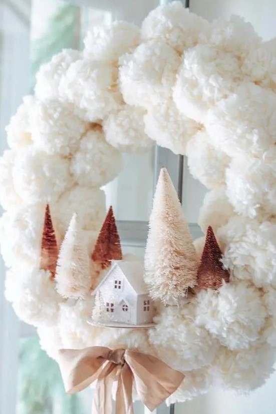 a delicate white pompom Christmas wreath with blush and rustic bottle brush trees and a mini house plus a mauve bow