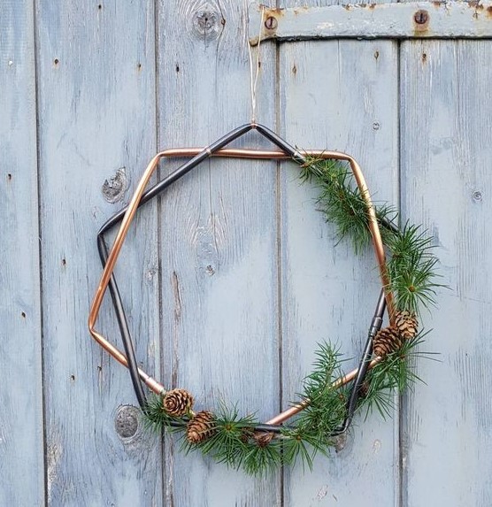 a geometric Christmas wreath with greenery and pinecones is a stylish and modern decor idea for the holidays