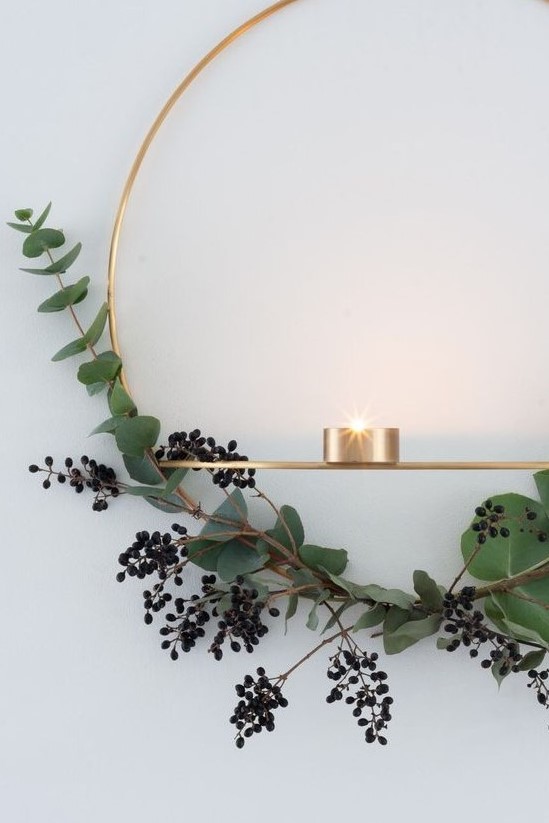 a gold wreath with privet berries and eucalyptus and some candleholders for a stylish minimalist space