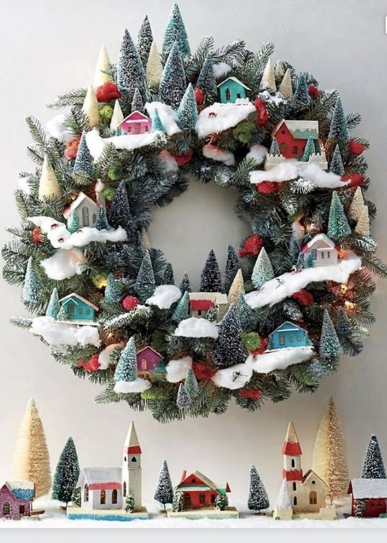 a jaw-dropping modern Christmas wreath of evergreens, little colorful houses and bottle brush trees is wow