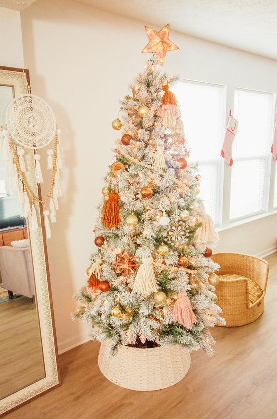 a lovely flocked Christmas tree with pastel boho decor, orange, gold and blush ornaments, beadsm large tassels and lights