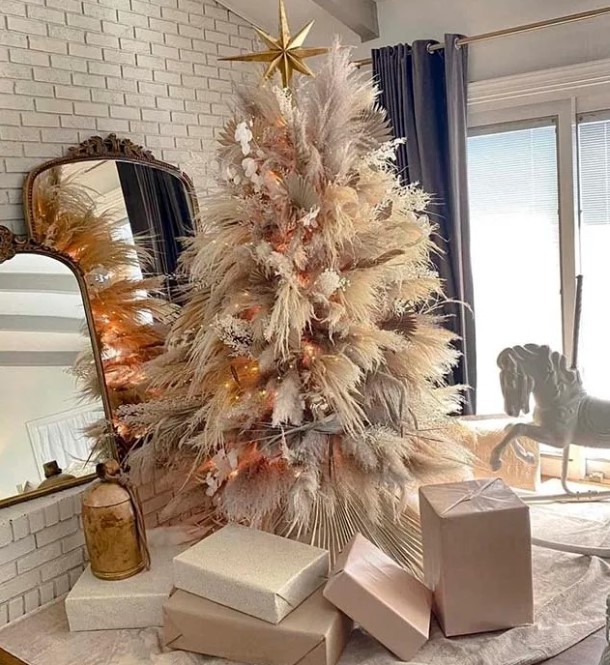 a luxurious pampas grass Christmas tree decorated with lights, neutral and pink blooms and fronds and topped with a gold star
