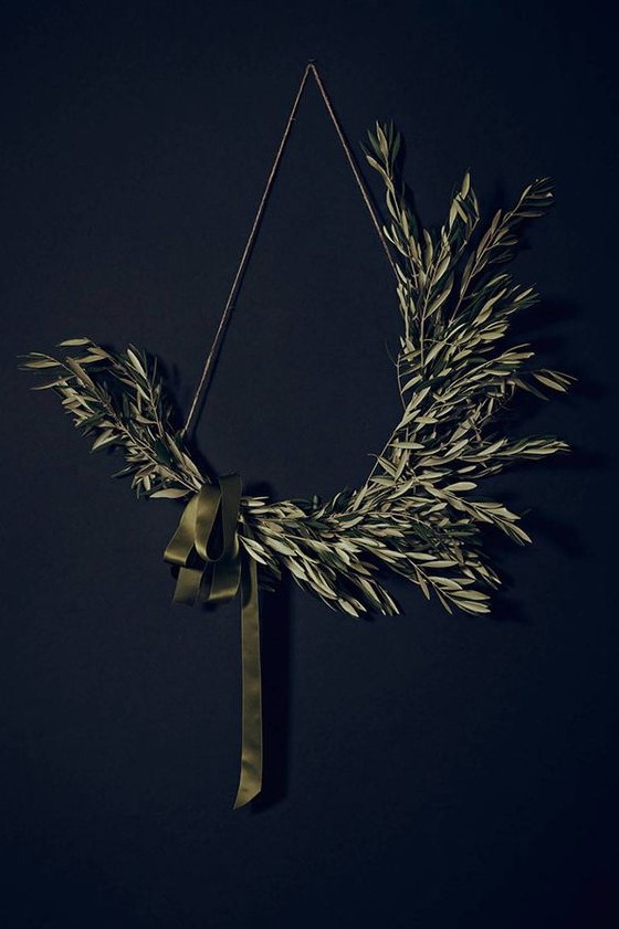a minimalist Christmas wreath of a triangle shape,w ith olive branches and a green ribbon bow is a stylish idea