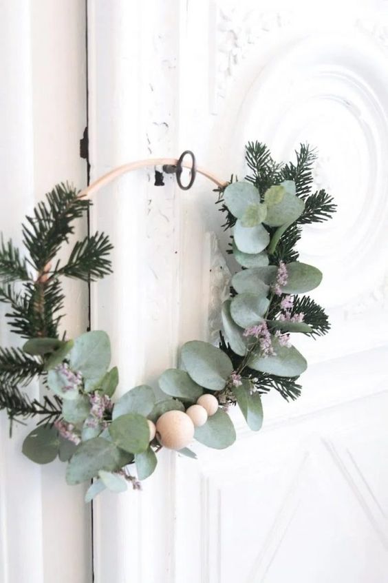 a modern Scandinavian Christmas wreath with evergreens, greenery and wooden beads is a cool and catchy idea