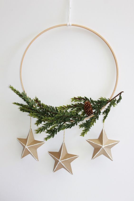 a modern Scandinavian wreath with evergreens, a pinecone and stars is a cool and catchy idea to go for