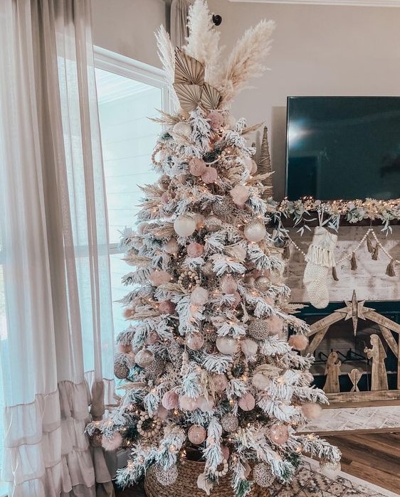 a neutral boho Christmas tree with creamy and pink ornaments, wooden beads, pampas grass and fronds and lights