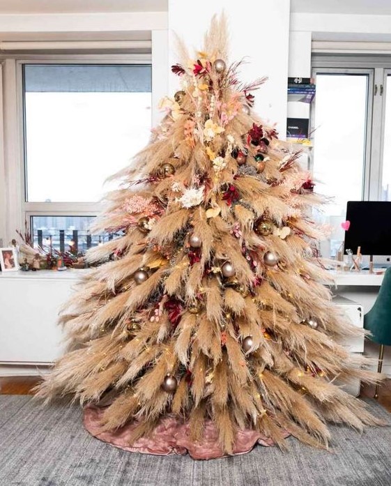 a pampas grass Christmas tree with neutral, pink and burgundy blooms and metallic ornaments plus lights