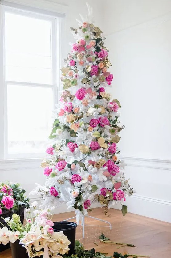 a romantic white Christmas tree decorated with hot pink and blush blooms, leaves and gilded foliage is super elegant