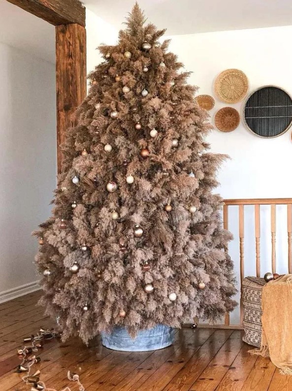 a rustic pampas grass christmas tree decorated with metallic and brown ornaments and lights looks very boho and cozy