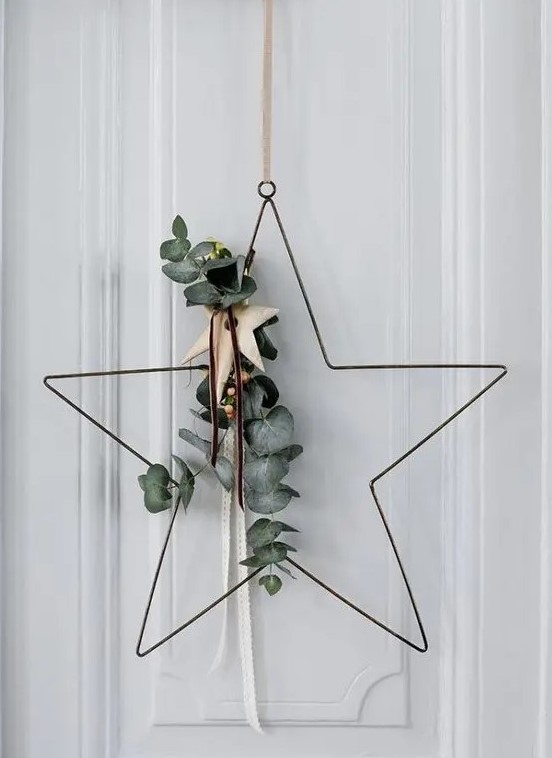 a star-shaped Christmas wreath with eucalyptus, with wooden stars is a cool and contemporary idea for door decor