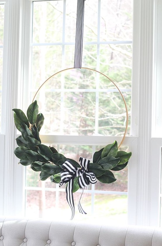a stylish and timeless modern Christmas wreath done with magnolia leaves and a black and white ribbon bow
