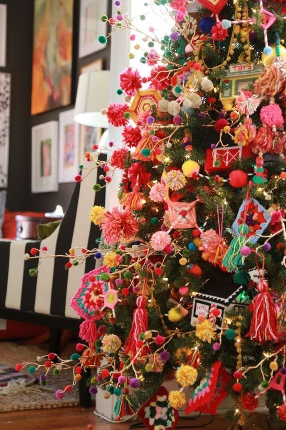 a super colorful Christmas tree decorated with bright pompom garlands and ornaments, with tassels, macrame and various yarn decor looks fun