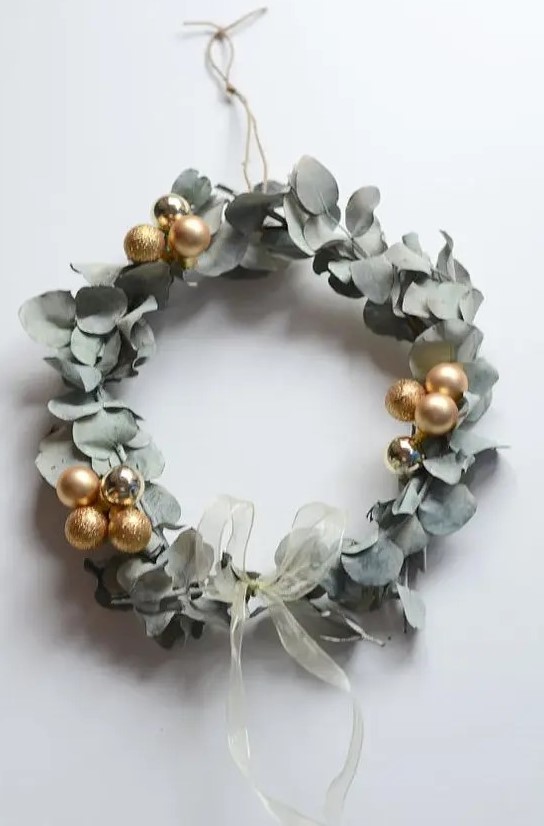 a super modern and bold eucalyptus and gold ornament wreath with a delicate ribbon bow is amazing for Christmas