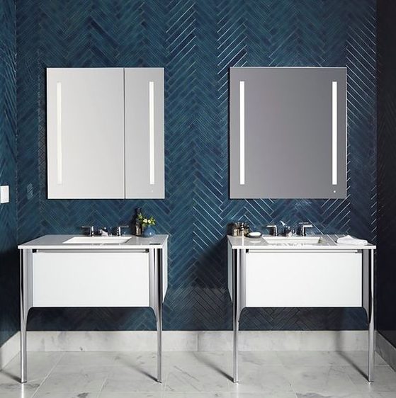 a bold contemporary bathroom wih teal skinny tiles clad in a chevron pattern and contrasting white vanities