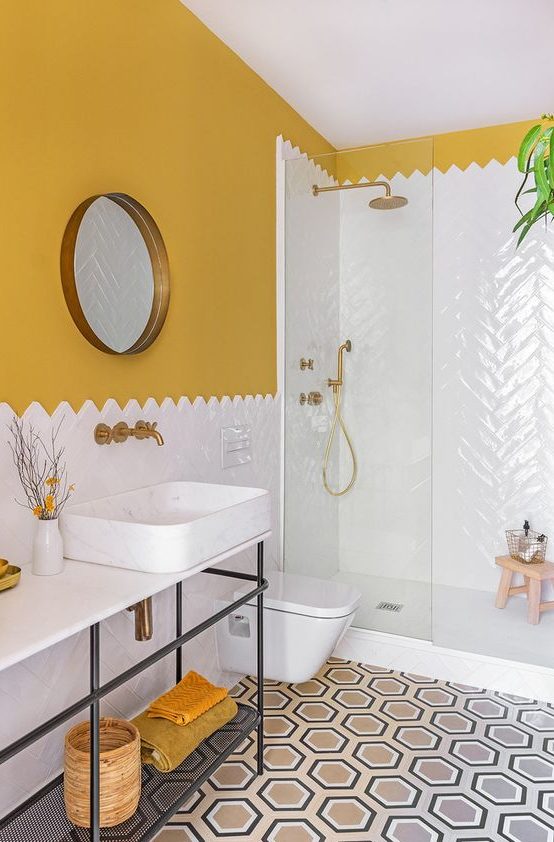 a colorful mid-century modern bathroom with mustard walls, a mosaic tile floor, a white tile shower space and mustard towels