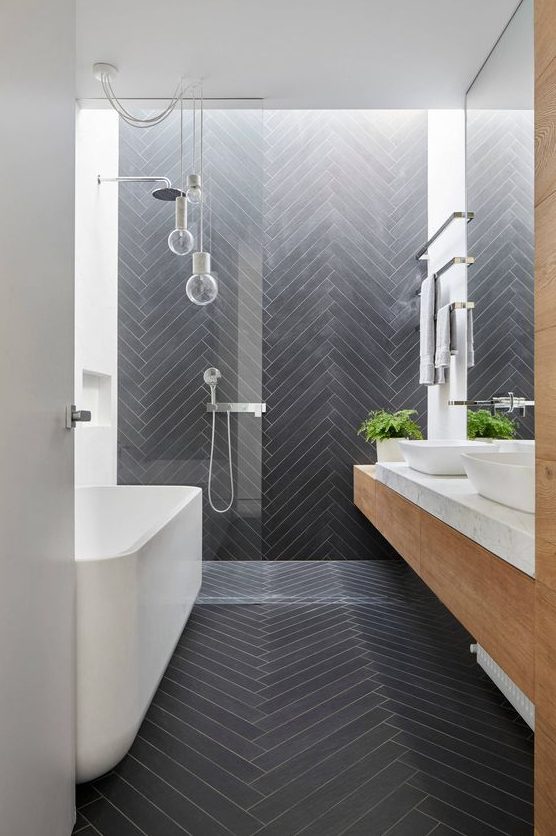 a contemporary bathroom clad with long and skinny graphite grey tiles in a chevron pattern