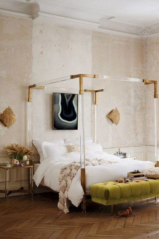 a creative Parisian bedroom with a catchy bed with acrylic framing, a green bench, catchy artworks and blush walls