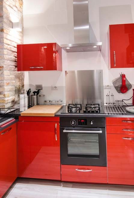 a hot red kitchen with metal countertops and a backsplash and stainless steel appliances is a lovely space