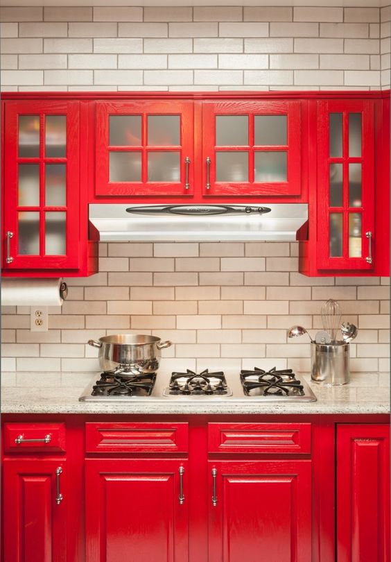 a hot red kitchen with vintage cabinets, a white tile backsplash and a white stone countertops is a cool space