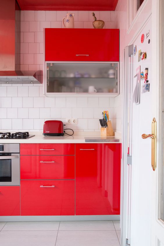 a hot red kitchen with white square tiles, stainless steel appliances and red ones is a lovely and catchy space