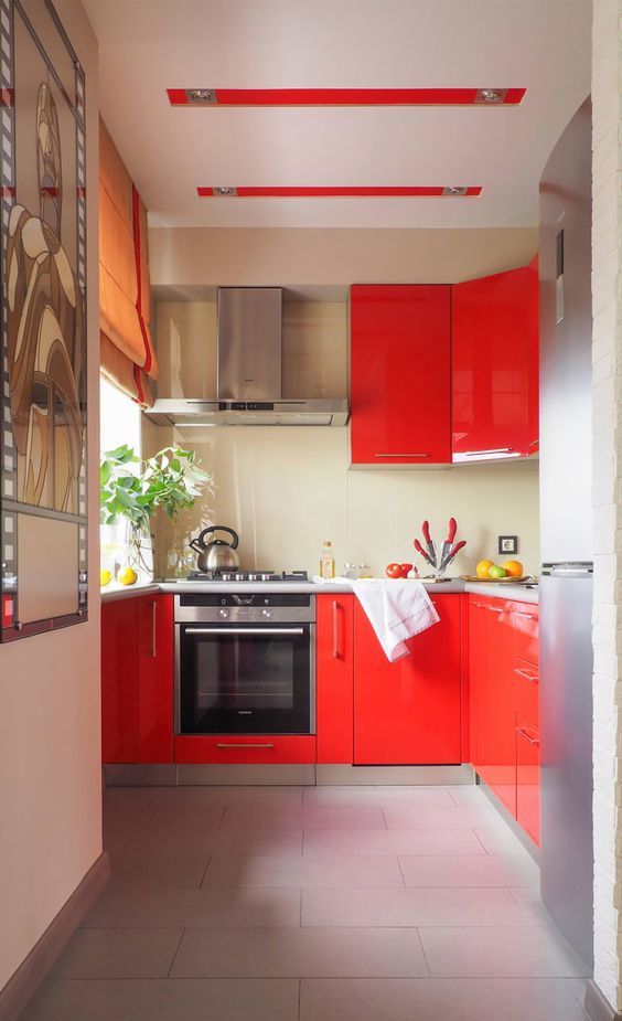 a modern bold red sleek and glossy kitchen with a tan backsplash to calm it down, neutral countertops and a stainless steel fridge
