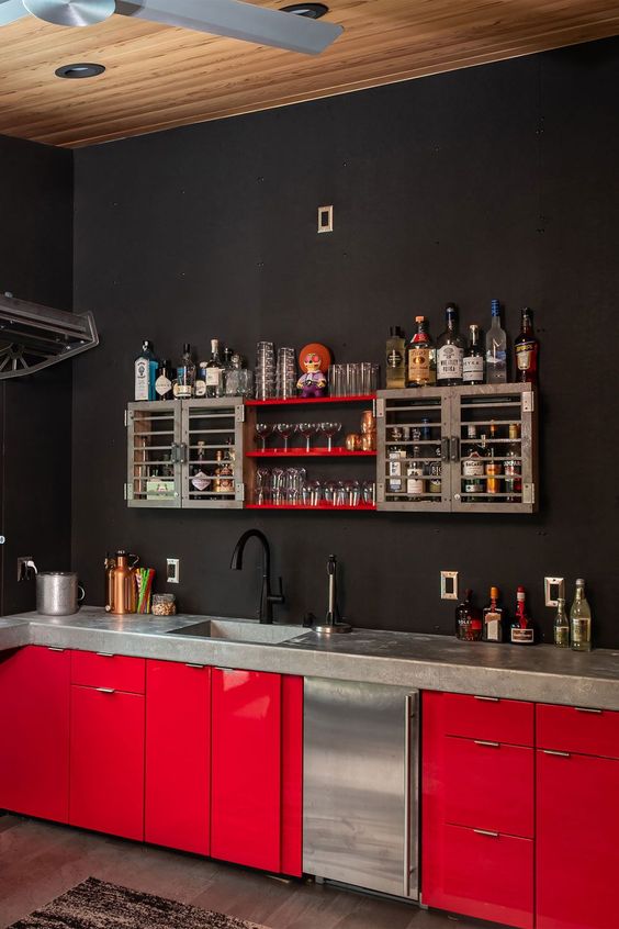 a moody black kitchen with matte walls and hot red lower cabinets, a home bar instead of upper ones is a unique space